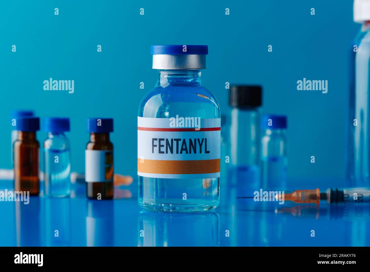 gros plan d'un flacon simulé de fentanyl sur une table bleue à côté d'une seringue et d'autres flacons différents Banque D'Images