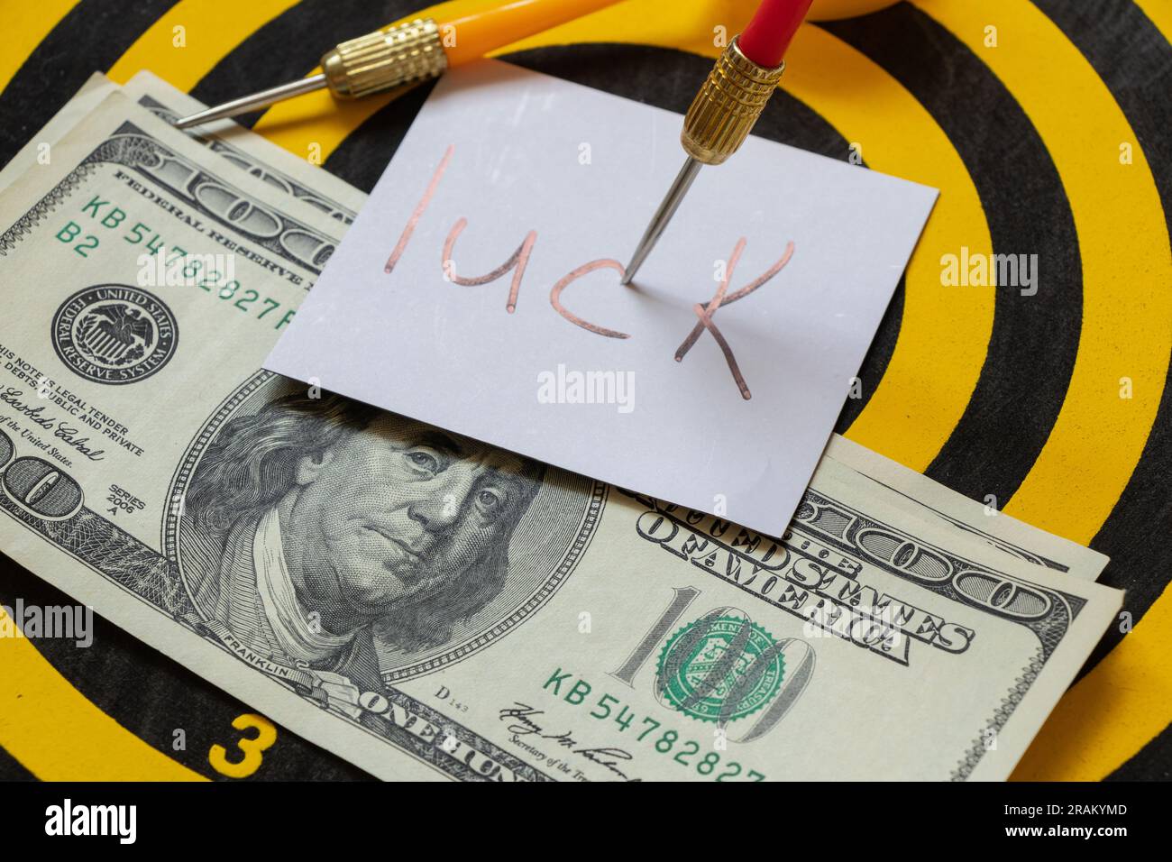 Cent dollars reposent sur les fléchettes et le texte bonne chance dans le centre de la cible et la fléchette, fortune et chance, affaires Banque D'Images