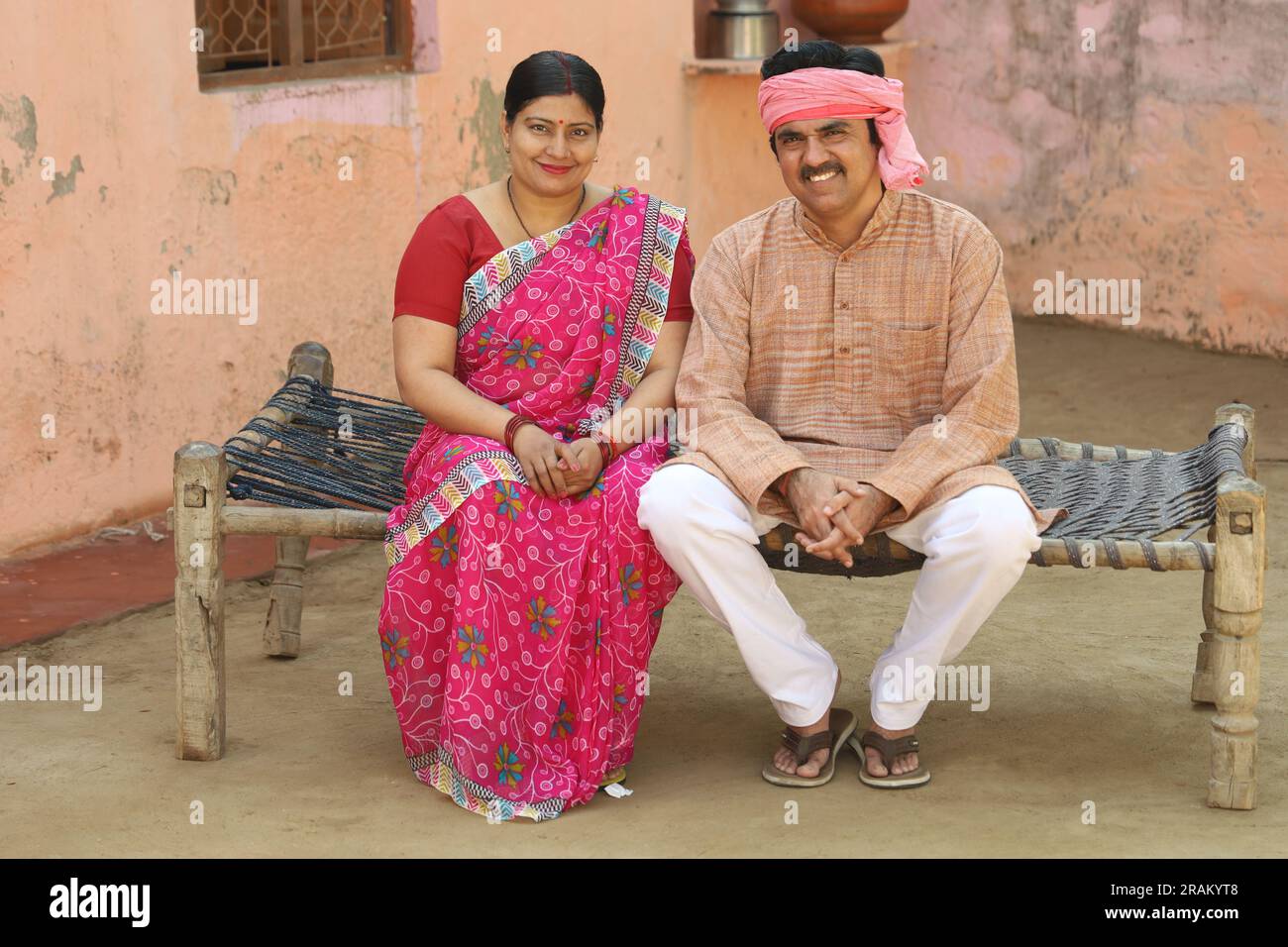 Couple de fermiers ruraux indiens assis dehors ensemble. Tenue vestimentaire du villageois indien. mari et femme assis sur le lit. Homme et femme indiens ruraux. Banque D'Images