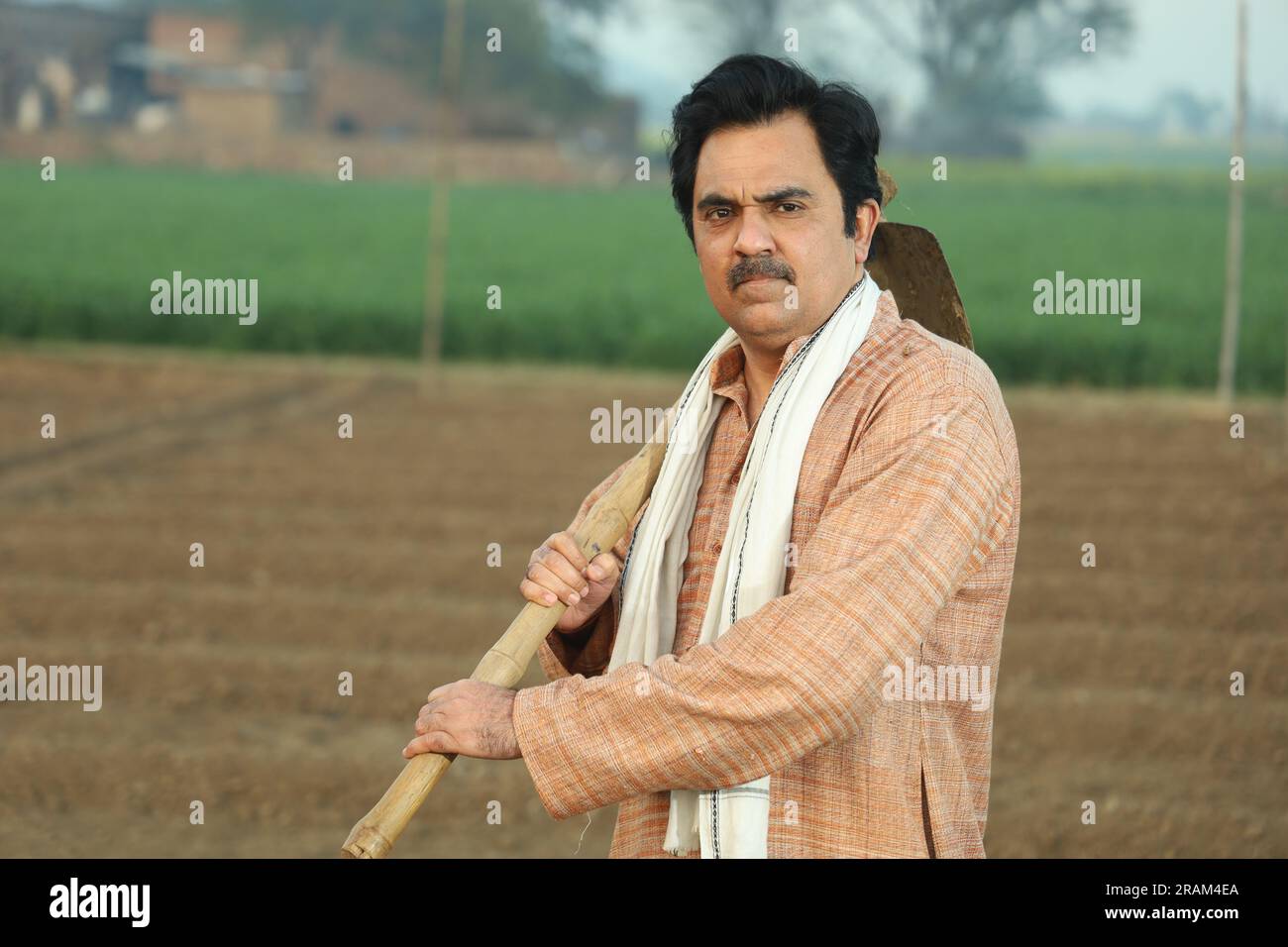 Portrait d'un fermier indien heureux labourant le champ manuellement en une journée. Tenir un outil agricole en main. Pelle et houe à outils de creusement en main. Banque D'Images