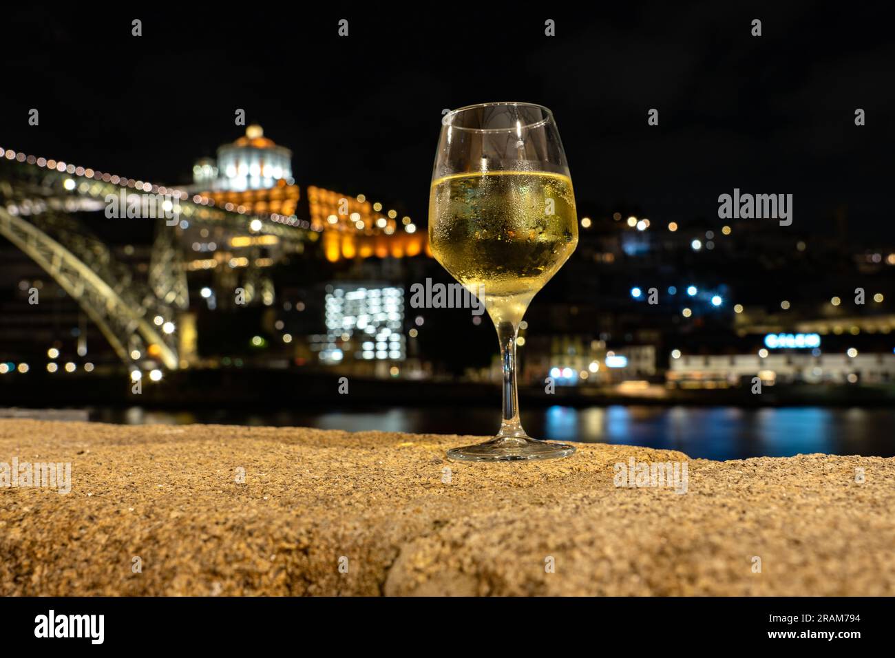 Boire du vin de Porto blanc dans un restaurant à Porto à côté de la rivière dans la soirée avec belle vue. Banque D'Images