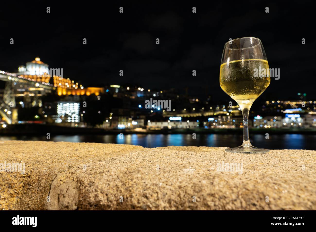 Boire du vin de Porto blanc dans un restaurant à Porto à côté de la rivière dans la soirée avec belle vue. Banque D'Images