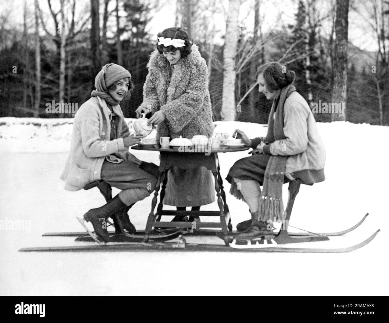 Lac Placid, New York : 3 janvier 1923. Deux jeunes patineuses au Lake Placid Club profitent d'un thé de l'après-midi servi chaud hors de la table de ski-thé. Banque D'Images