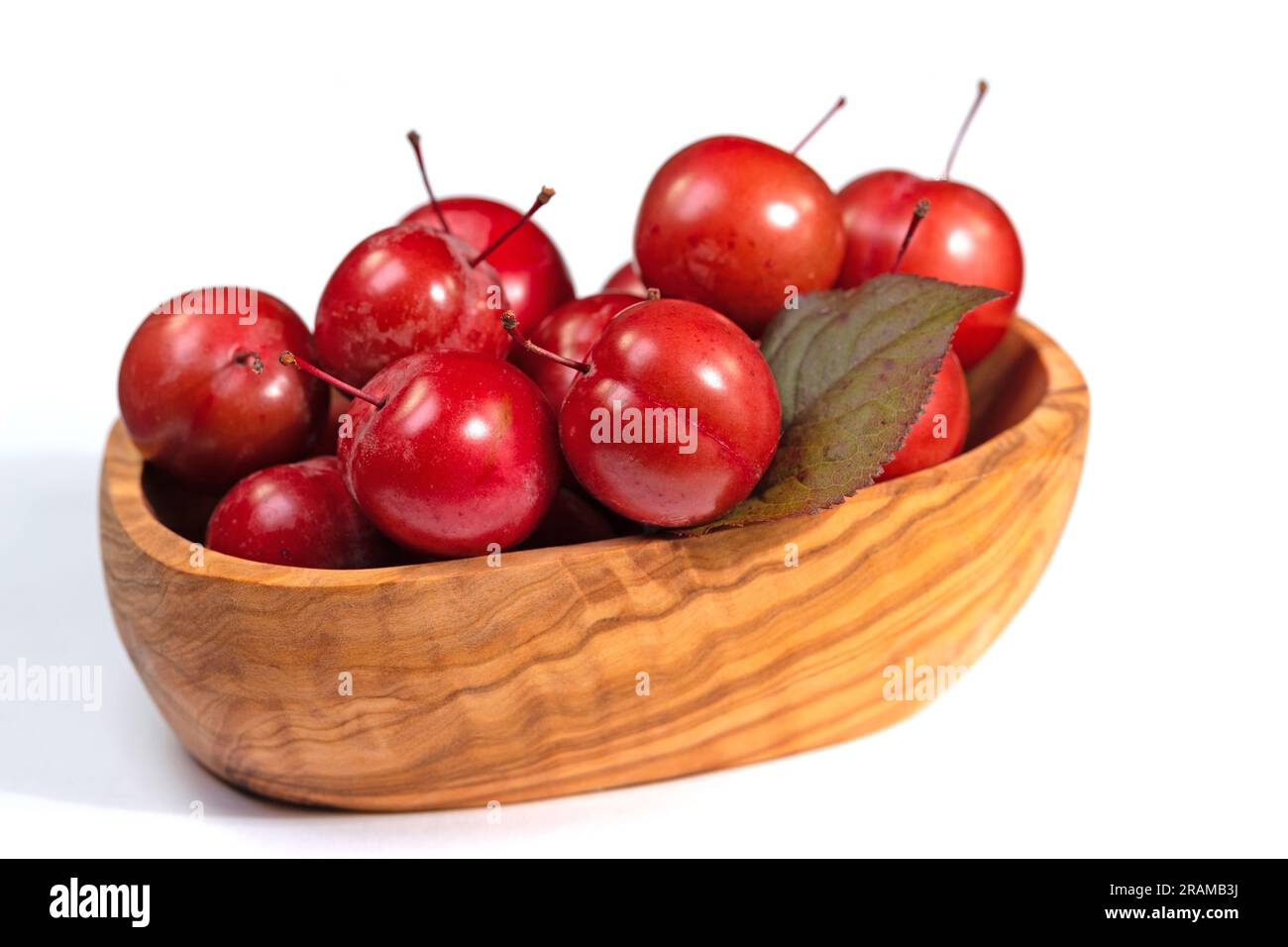 Prunes cerisières, Prunus cerasifera, dans un bol en bois Banque D'Images