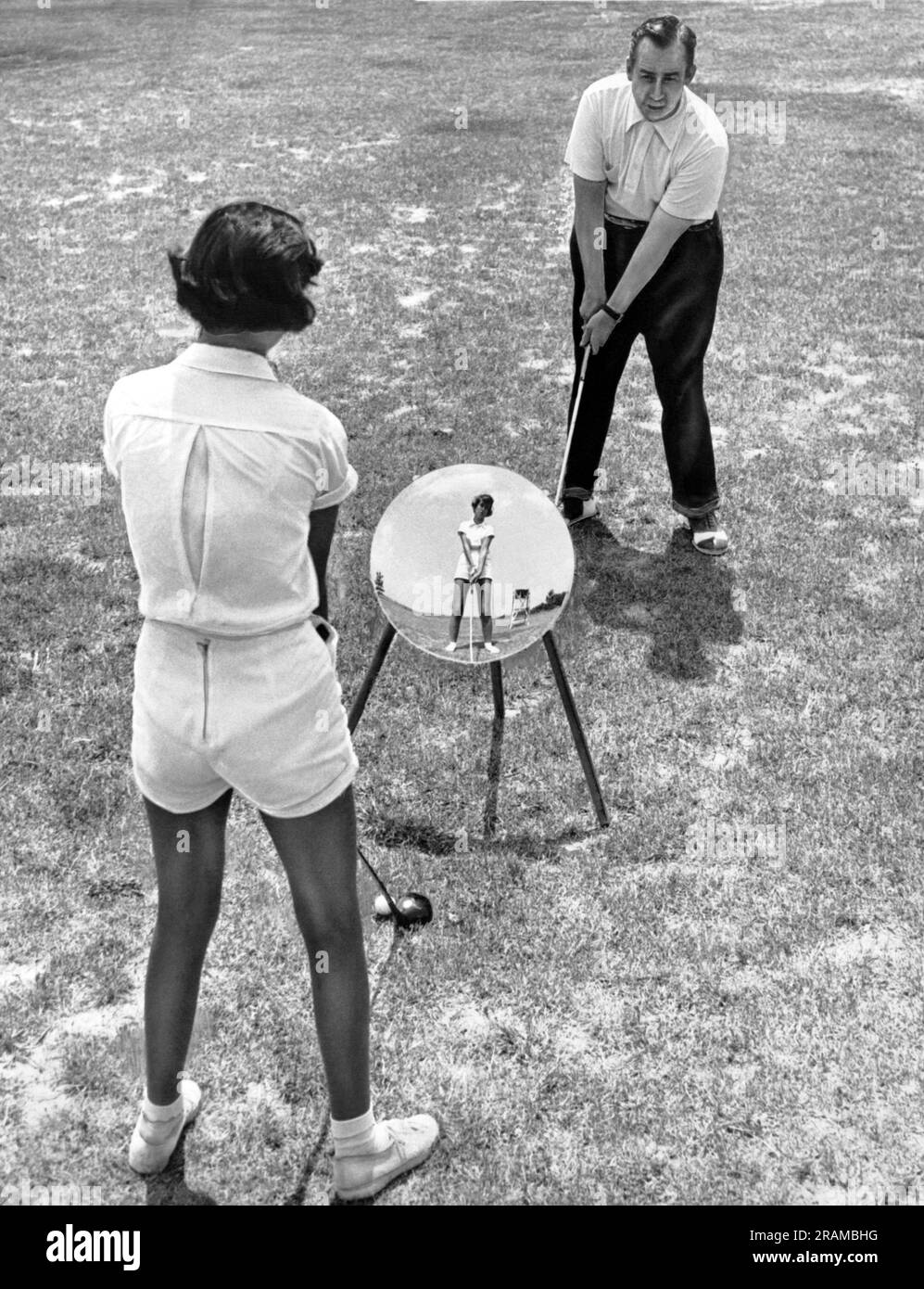 St. Louis, Missouri: 1 mai 1951 golfeur professionnel Hinterpel enseigne à un étudiant une technique qu'il a développée. Il apprend à balancer à gauche de sorte qu'en utilisant un miroir, ses étudiants puissent comparer leur balancement à sa forme parfaite Banque D'Images