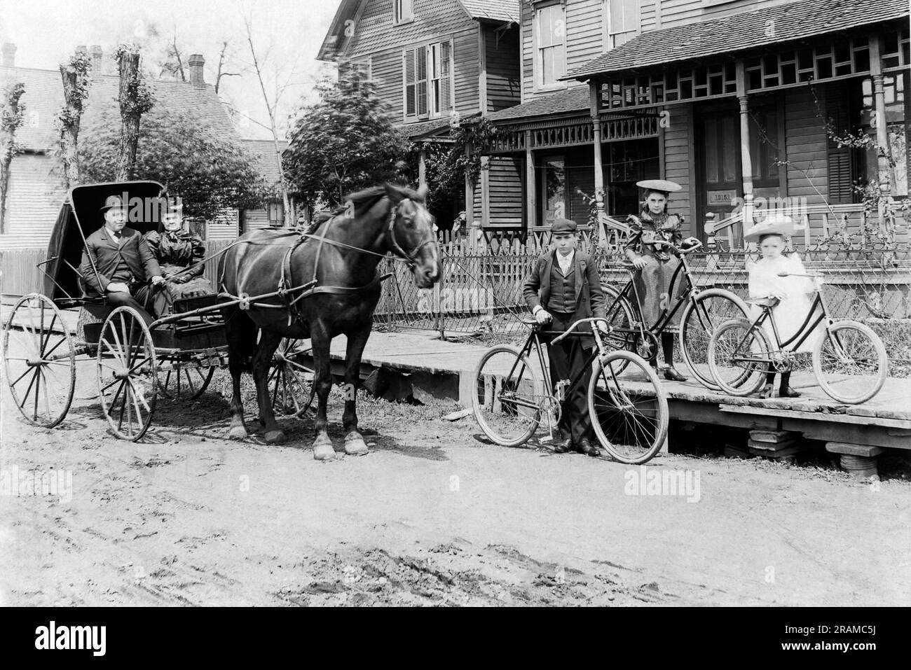 États-Unis : c. 1885 Une scène de rue de village avec un cheval et une poussette, des bicyclettes et des trottoirs surélevés. Banque D'Images