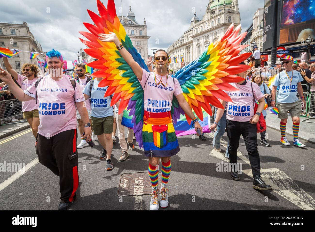 Homme agitant avec des ailes arc-en-ciel et kilt participant à la parade Pride in London Banque D'Images