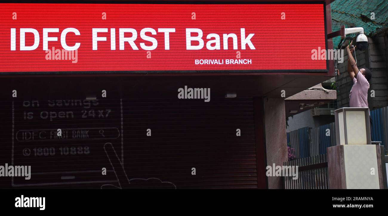 Un homme fixe une caméra de télévision en circuit fermé (CCTV) à côté de l'écran à diodes électroluminescentes (LED) de la première succursale de la banque IDFC à Mumbai. IDFC First Bank fusionne avec IDFC Limited. 155 actions de la première banque de la FIDC seront attribuées pour 100 actions de la FIDC Banque D'Images