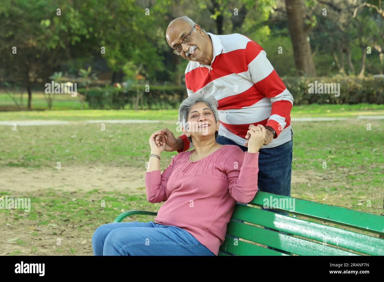 Couple de vieillesse assis sur le banc dans un environnement verdoyant et serein ayant un bon moment ensemble. Ils profitent joyeusement de leur temps. Banque D'Images