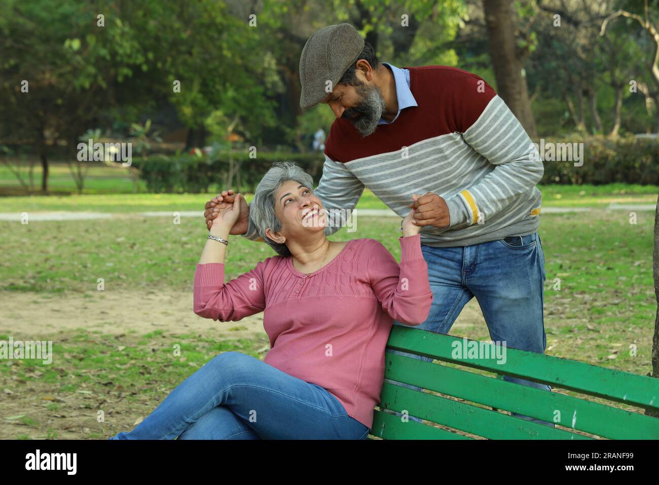 Couple de vieillesse assis sur le banc dans un environnement verdoyant et serein ayant un bon moment ensemble. Ils profitent joyeusement de leur temps. Banque D'Images