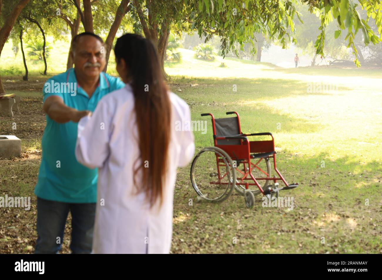 Médecin indien féminin prenant soin du patient âgé dans le jardin de l'hôpital. Le patient est incapable de marcher Banque D'Images