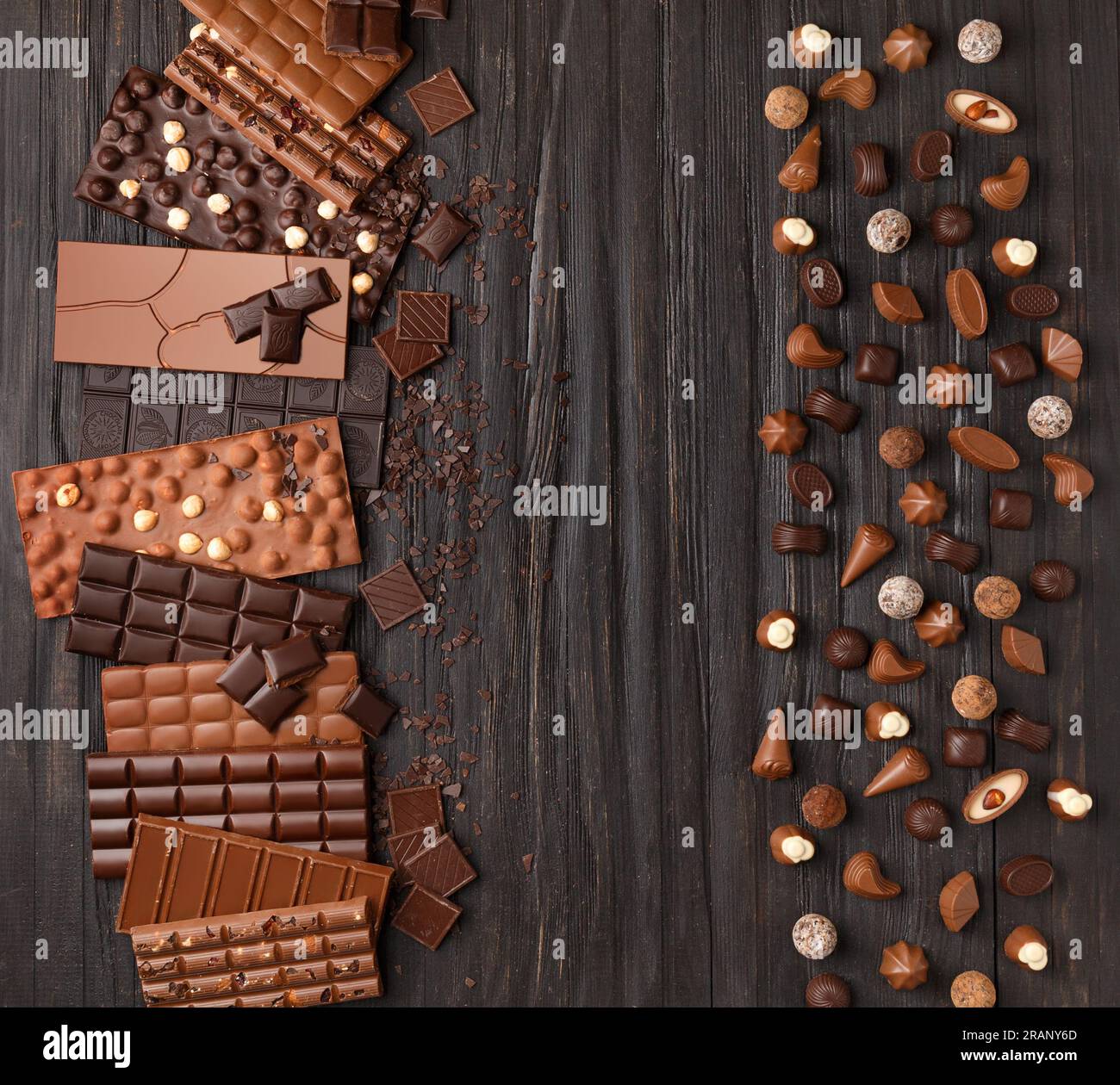 Divers bonbons au chocolat noir et au lait et bâtons de chocolat, truffes au chocolat sur une texture en bois sombre vue de dessus. Banque D'Images