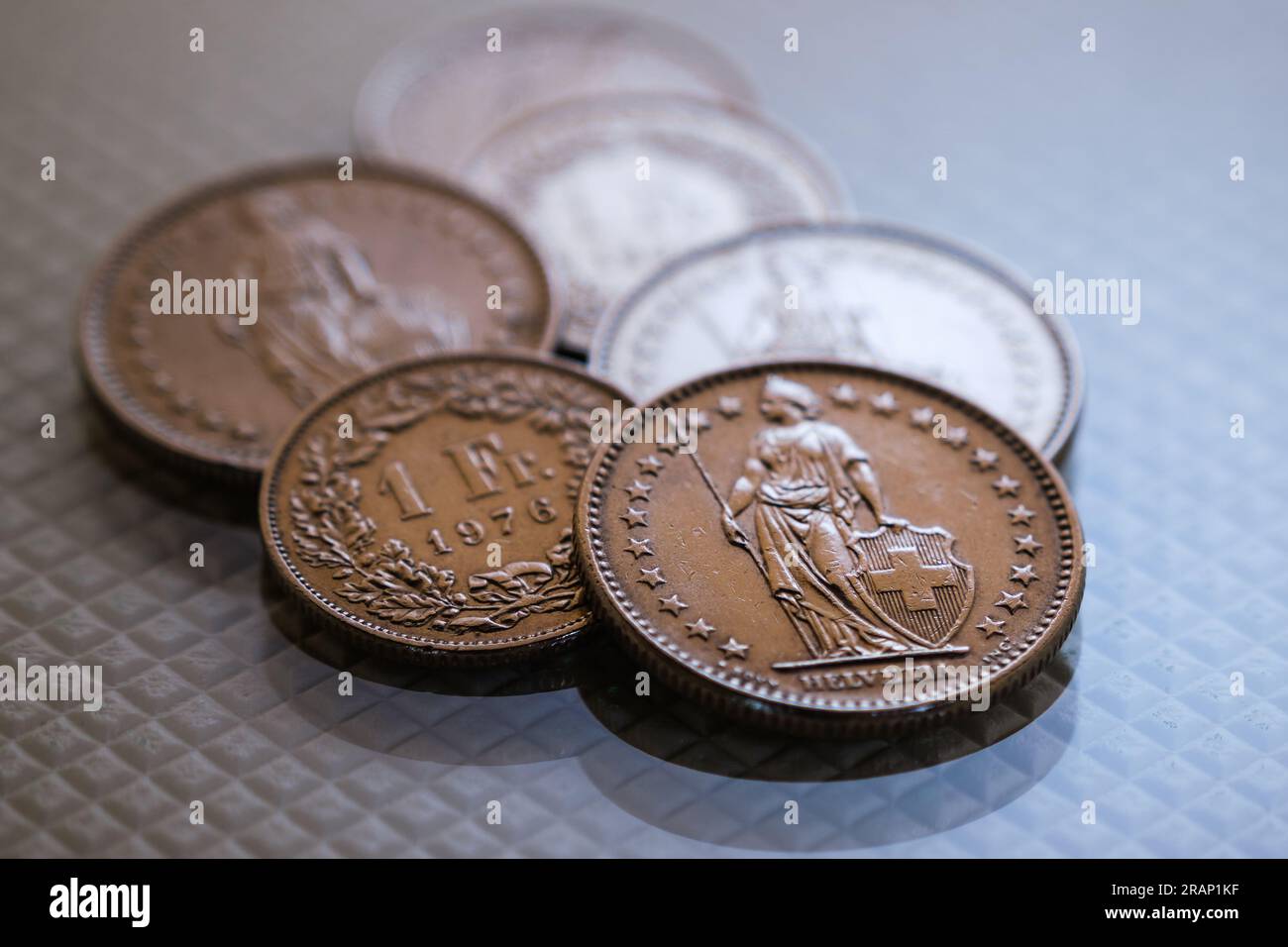 Quelques pièces de franc suisse reposant sur une base texturée blanche brillante. Banque D'Images