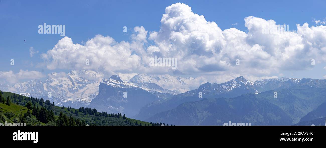 Pente de montagne verte en face du Mont Blanc sommets de neige éternels massifs dans la brume atmosphérique avec des nuages spectaculaires s'élevant au-dessus vu du Col de Joux Plan Banque D'Images