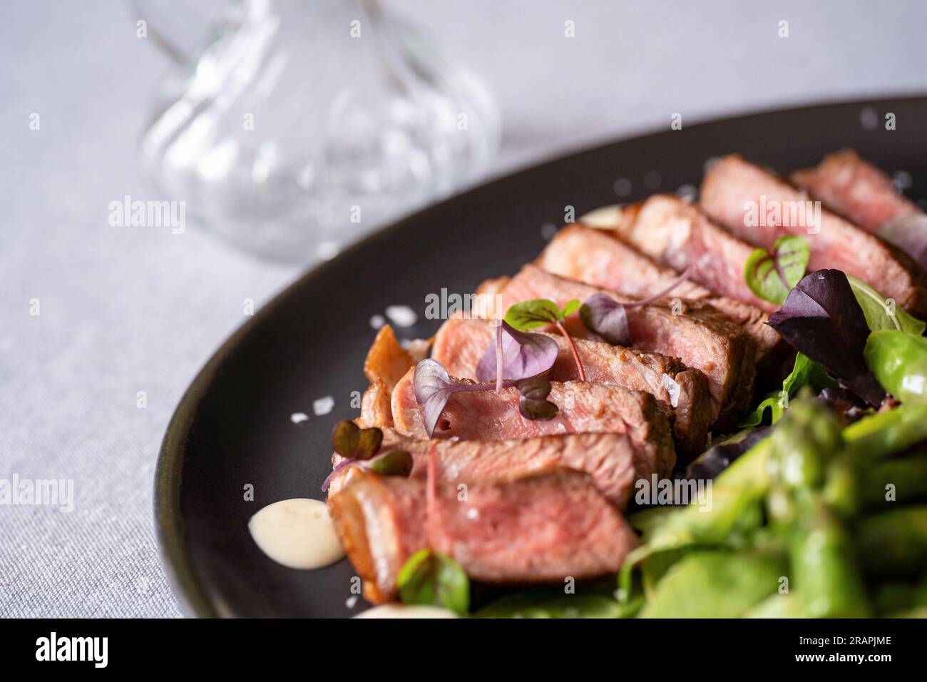 Steak de bœuf rôti tranché avec salade sur une assiette noire. Mise au point sélective. Cuisine gastronomique. Banque D'Images