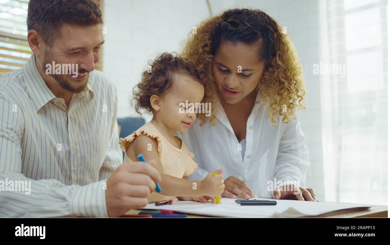Papa, maman et petite fille dessinant avec des crayons colorés sur papier heureux souriant.Jeune famille passent du temps libre ensemble dans le salon à la maison. Banque D'Images