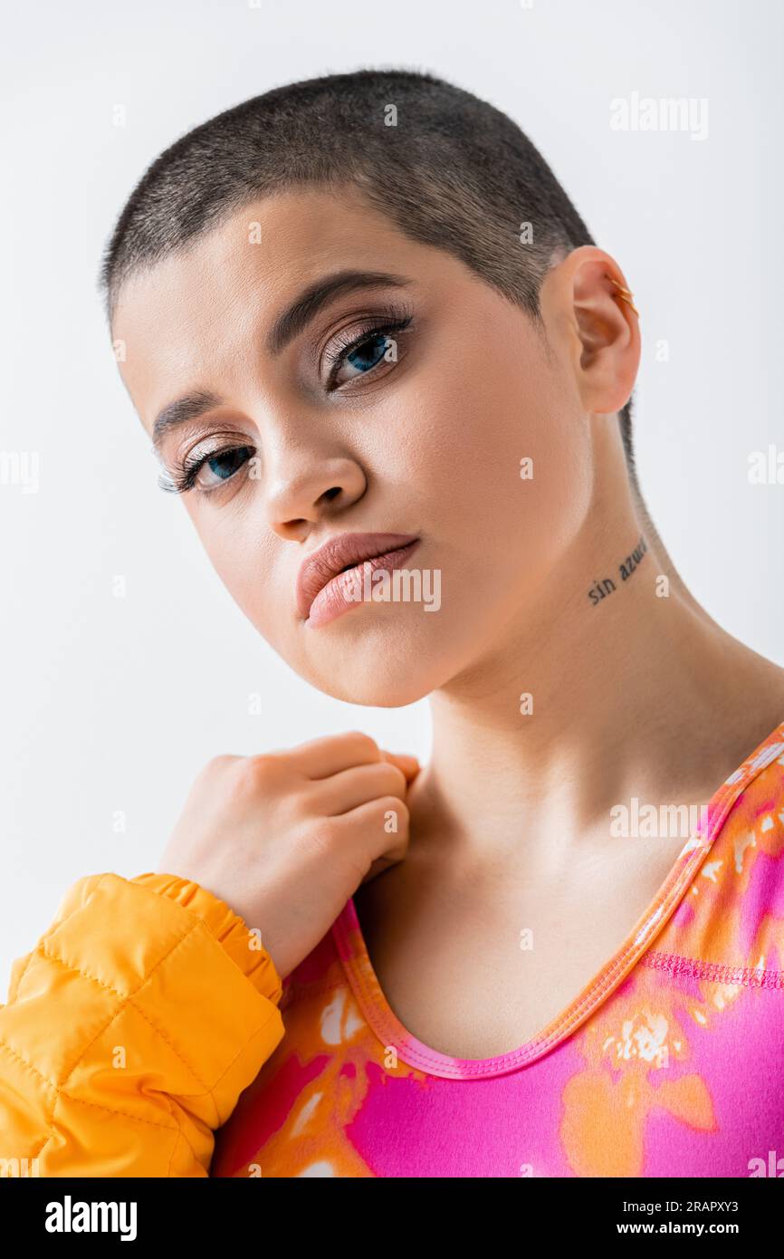 maquillage et style, style personnel, portrait de jeune femme tatouée aux cheveux courts regardant la caméra sur fond gris, génération z, tendance, mode Banque D'Images