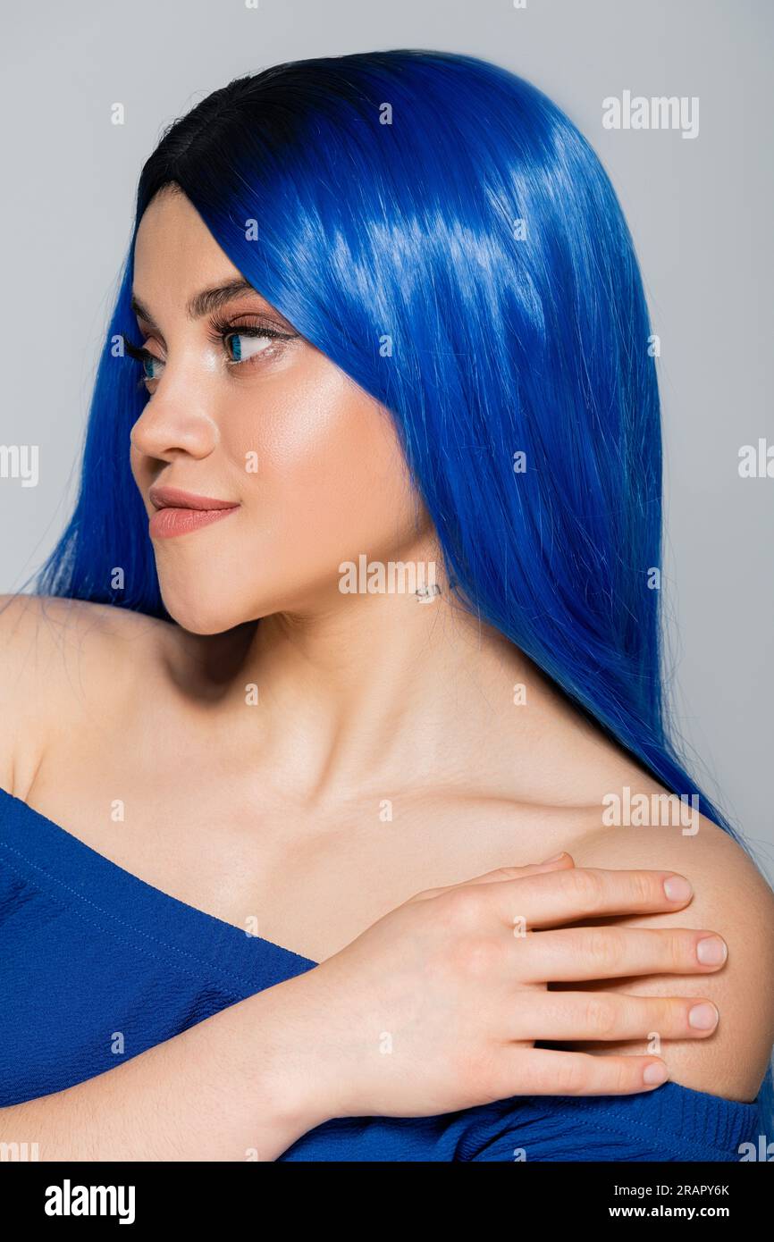 peau éclatante et jeunesse, femme tatouée avec des cheveux teints en bleu regardant loin sur fond gris, coiffure, cheveux bleus, beauté moderne, expression de soi, indi Banque D'Images