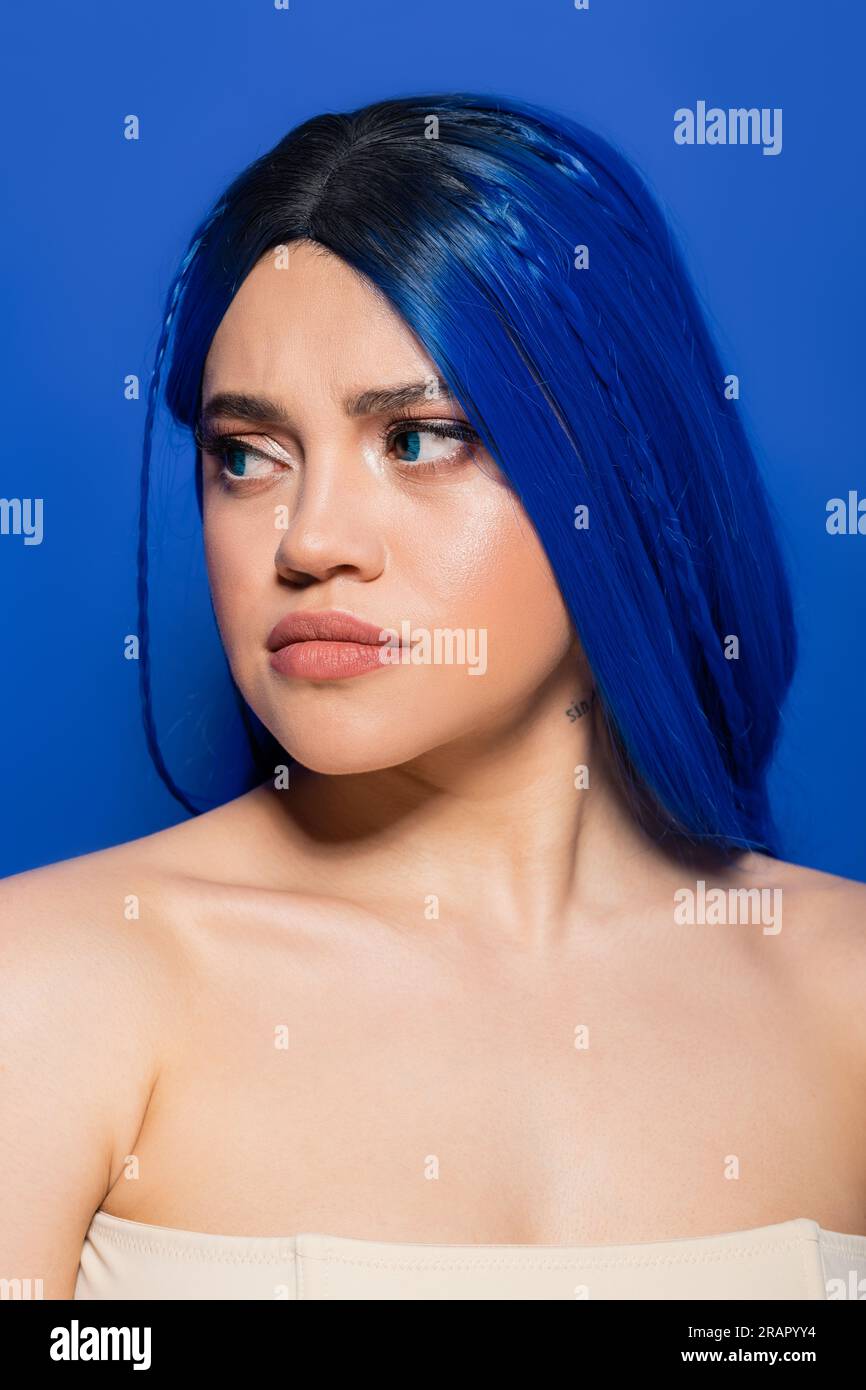 concept des tendances de beauté, portrait de jeune femme mécontente avec les cheveux teints posant sur fond bleu, couleur des cheveux, individualisme, modèle féminin avec makeu Banque D'Images
