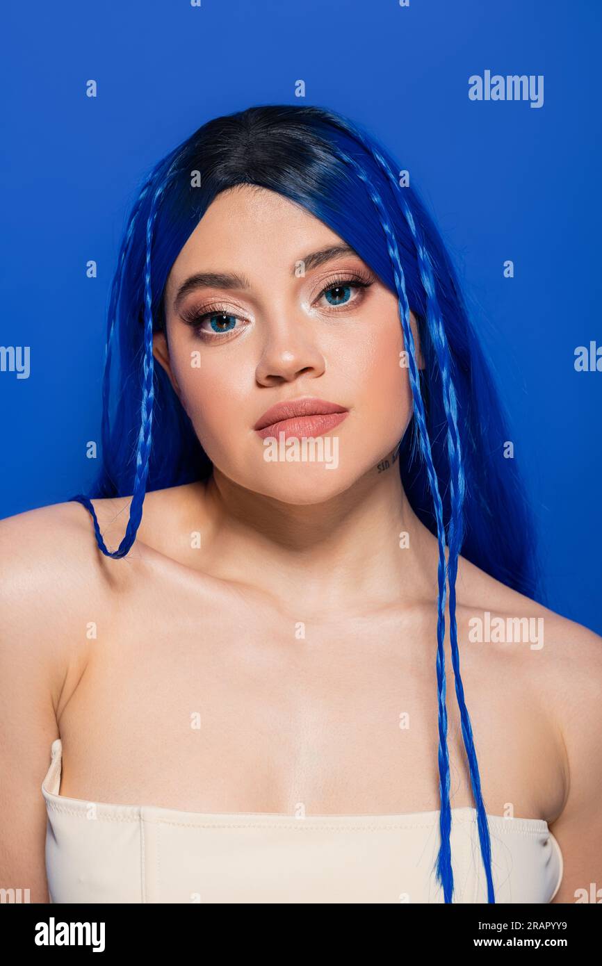 concept de beauté, jeune femme aux cheveux teints et à la peau éclatante posant sur fond bleu, couleur des cheveux, individualisme, modèle féminin avec maquillage et tendance Banque D'Images