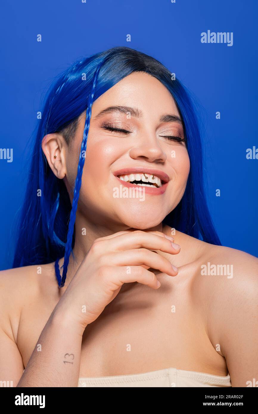 concept de beauté, jeune femme heureuse avec cheveux teints posant sur fond bleu, couleur des cheveux, individualisme, modèle féminin avec maquillage et coiffure tendance s Banque D'Images