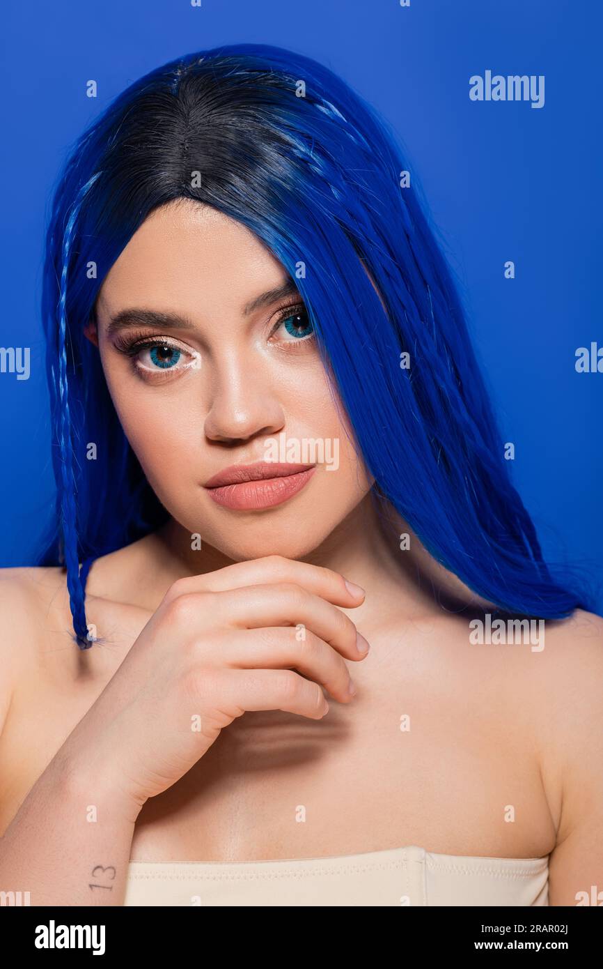 concept des tendances de beauté, jeune femme avec les cheveux teints posant sur fond bleu, couleur des cheveux, individualisme, modèle féminin avec maquillage et coiffure tendance, Banque D'Images