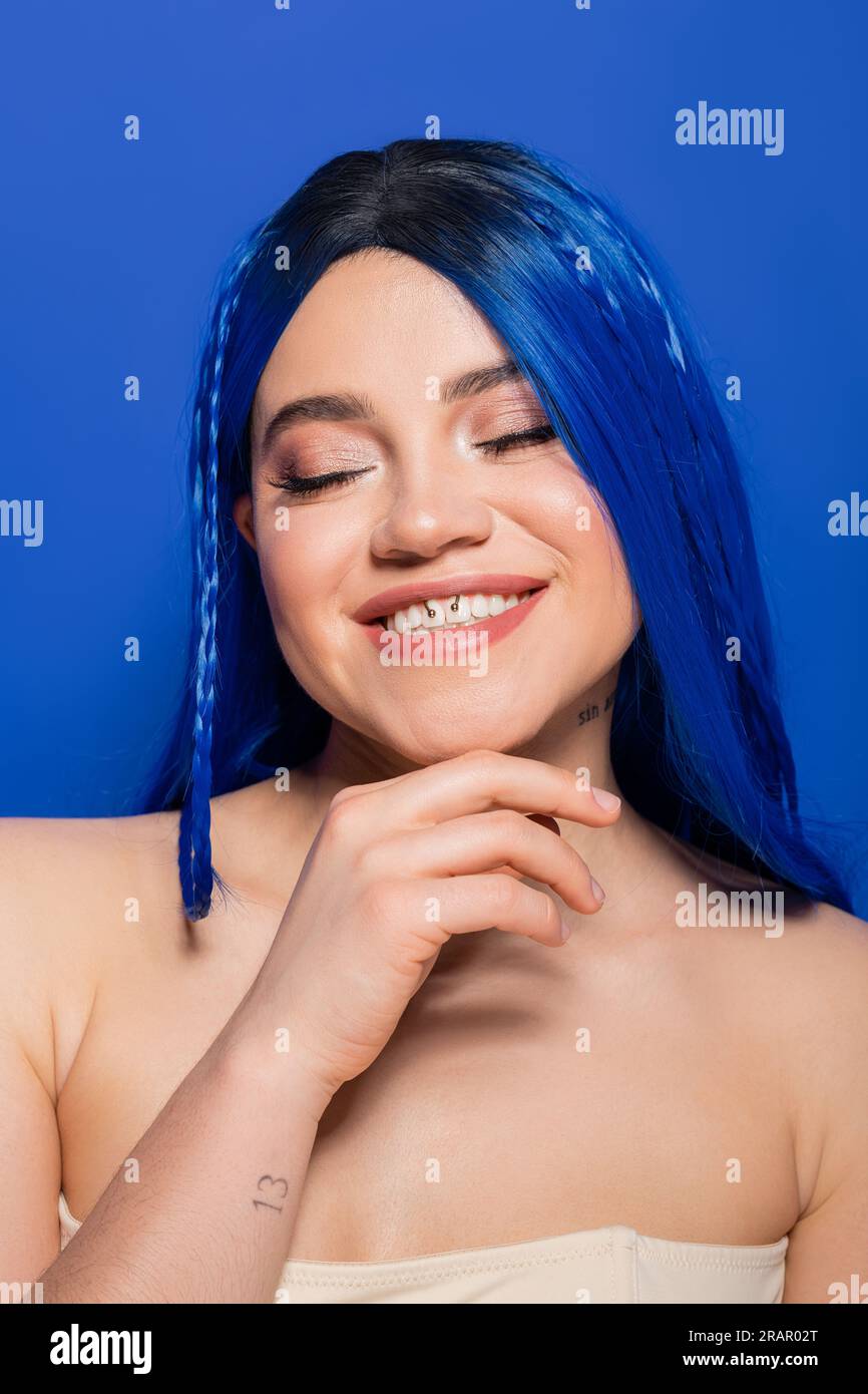 concept des tendances de beauté, jeune femme heureuse avec les cheveux teints posant sur fond bleu, couleur des cheveux, individualisme, modèle féminin avec maquillage et cheveux à la mode Banque D'Images