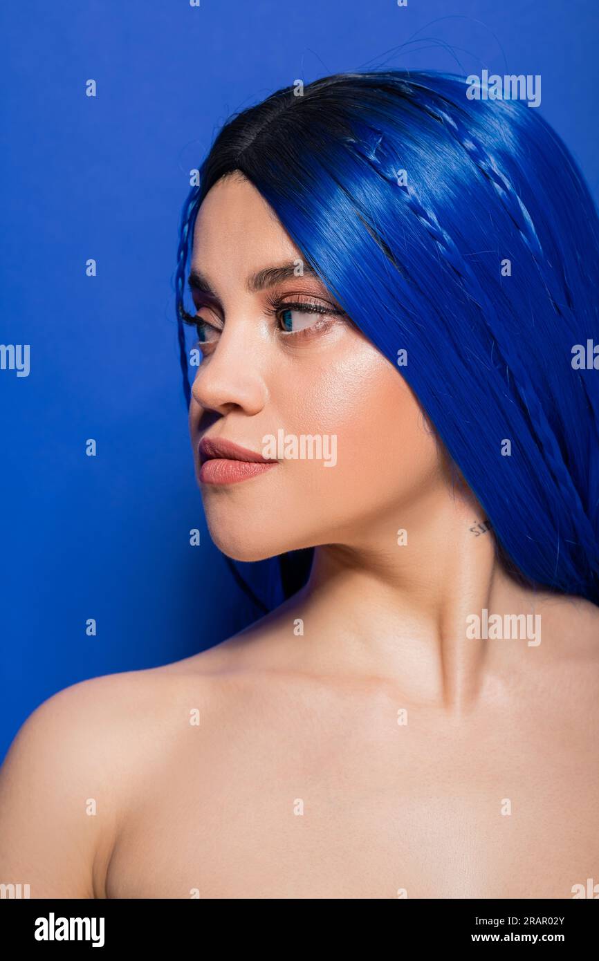 concept de jeunesse vibrant, jeune femme tatouée avec cheveux teints posant sur fond bleu, couleur des cheveux, individualisme, modèle féminin avec maquillage et h tendance Banque D'Images
