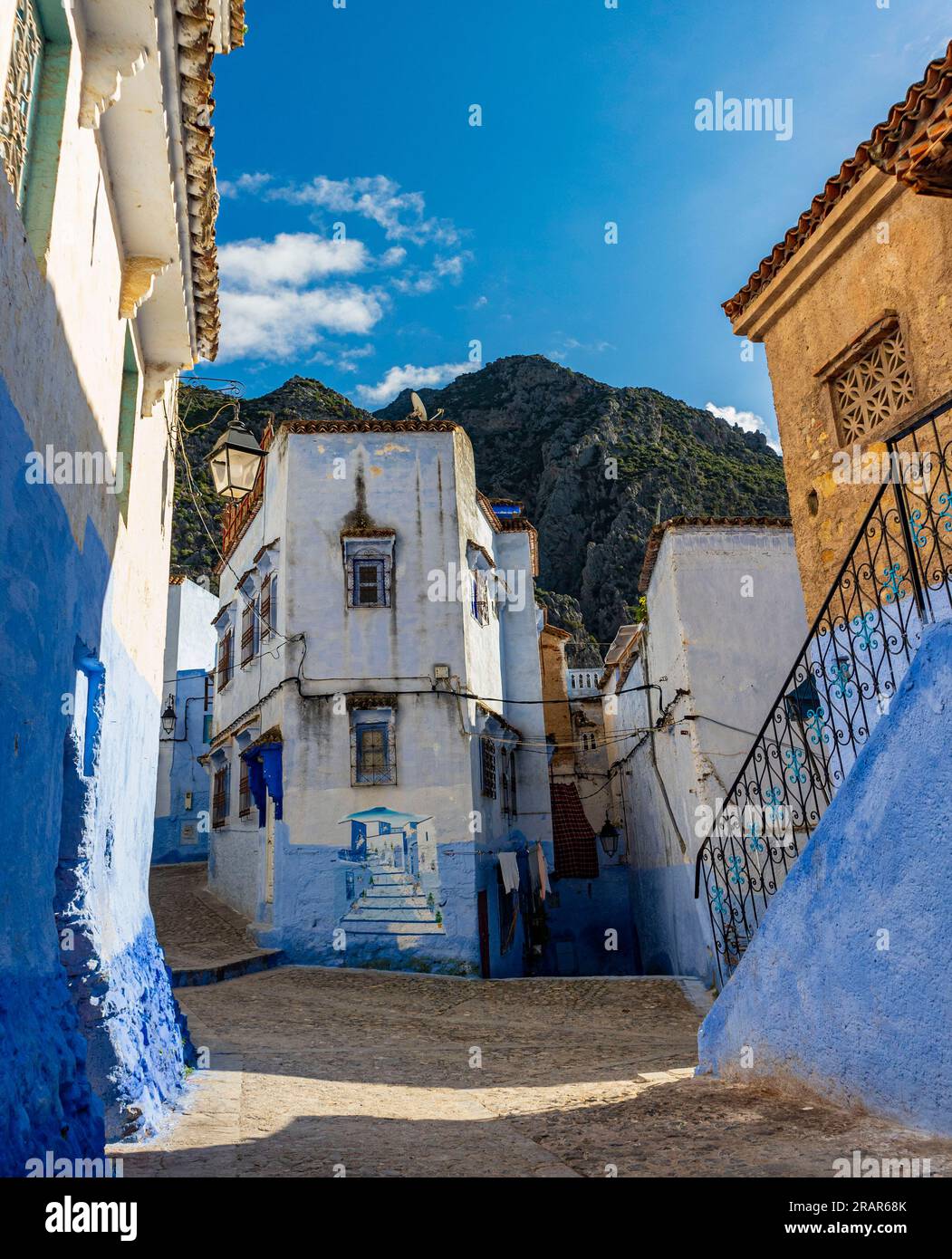 Une jonction dans les ruelles étroites de la ville bleue avec des montagnes imposantes en arrière-plan Banque D'Images