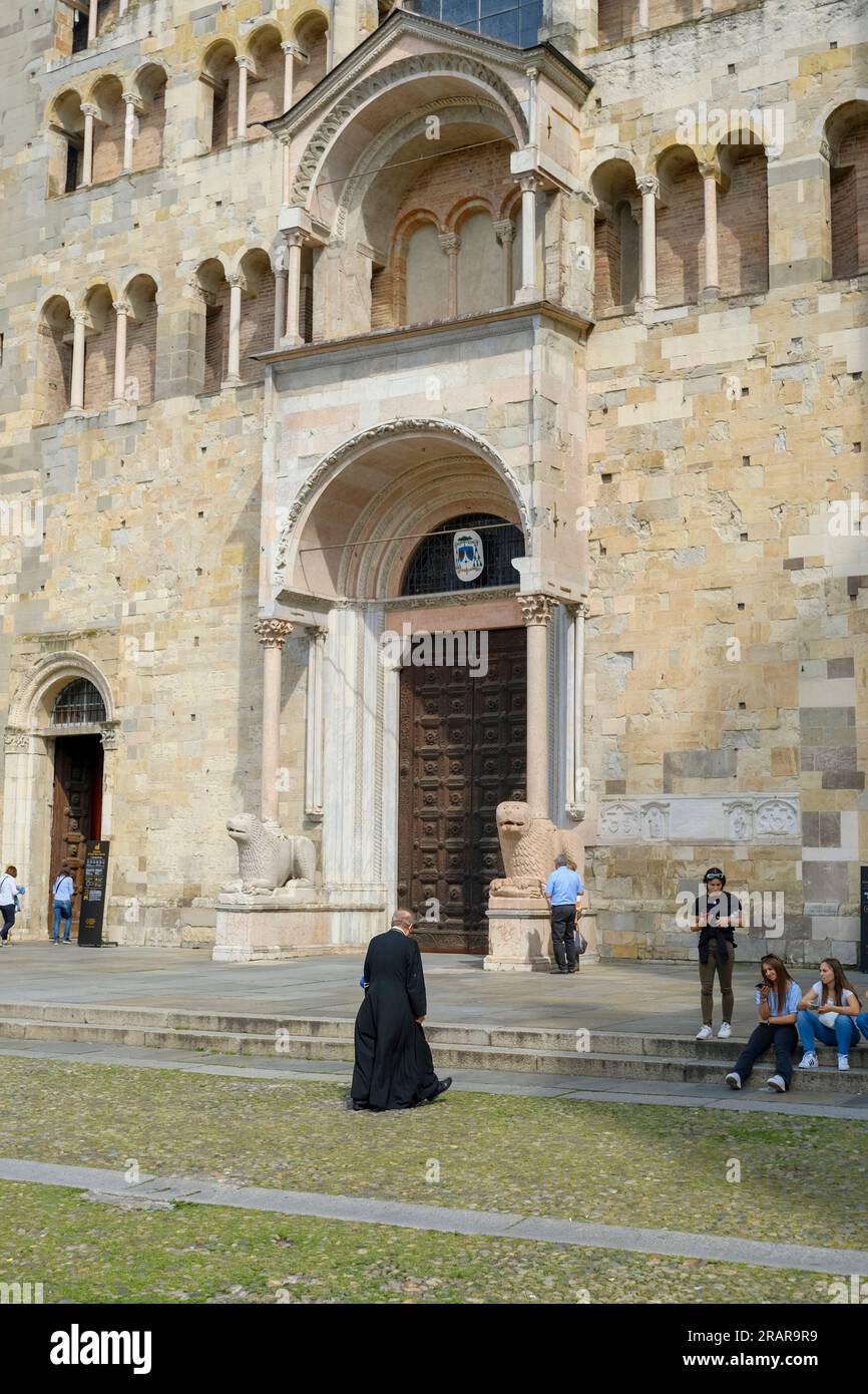 Le prêtre en uniforme noir se dirige vers la cathédrale de Parme par une journée ensoleillée Banque D'Images