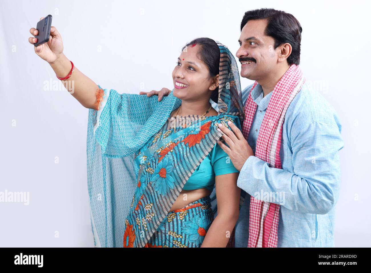 Couple de village indien rural prenant heureux un selfie à partir d'un téléphone portable. Femme portant Saree et homme en kurta. Banque D'Images