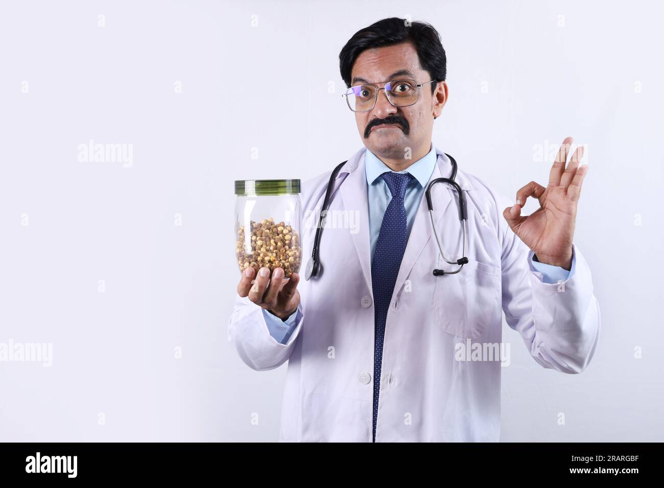 Docteur confiant indien tenant un pot en main et suggérant de manger frais et sain. Le docteur debout sur un fond blanc. Banque D'Images