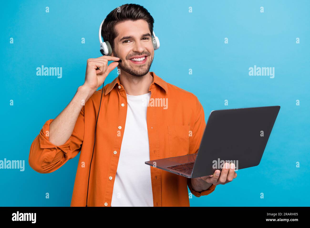 Portrait de positif beau gars de l'opérateur de helpdesk main touch casque microphone utiliser netbook isolé sur fond bleu Banque D'Images
