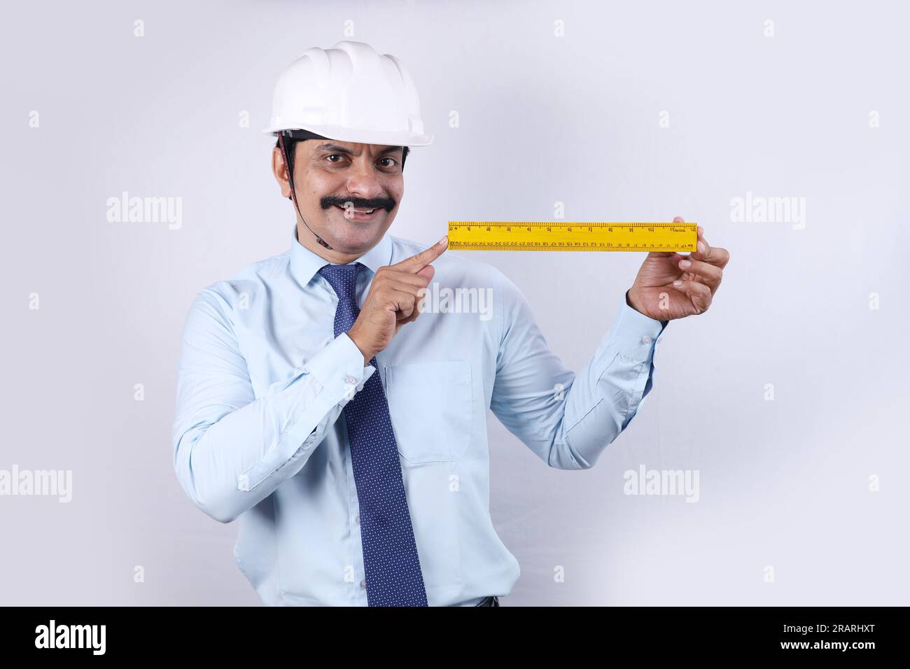 Heureux travailleur indien de construction faisant le concept d'ingénieur pour l'avenir. L'ingénieur joyeux porte un casque d'ingénierie. Graduation de mesure de maintien. Banque D'Images