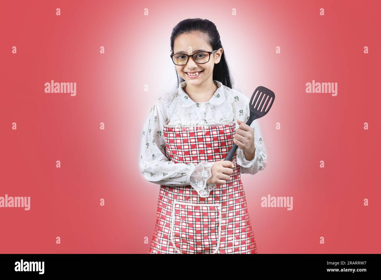Portrait d'une adolescente indienne heureuse dans la cuisine tenant des accessoires de cuisine. Rolling Rin, cuillère à frire, louche, poêle à frire. Joyeux et joyeux jeune Banque D'Images