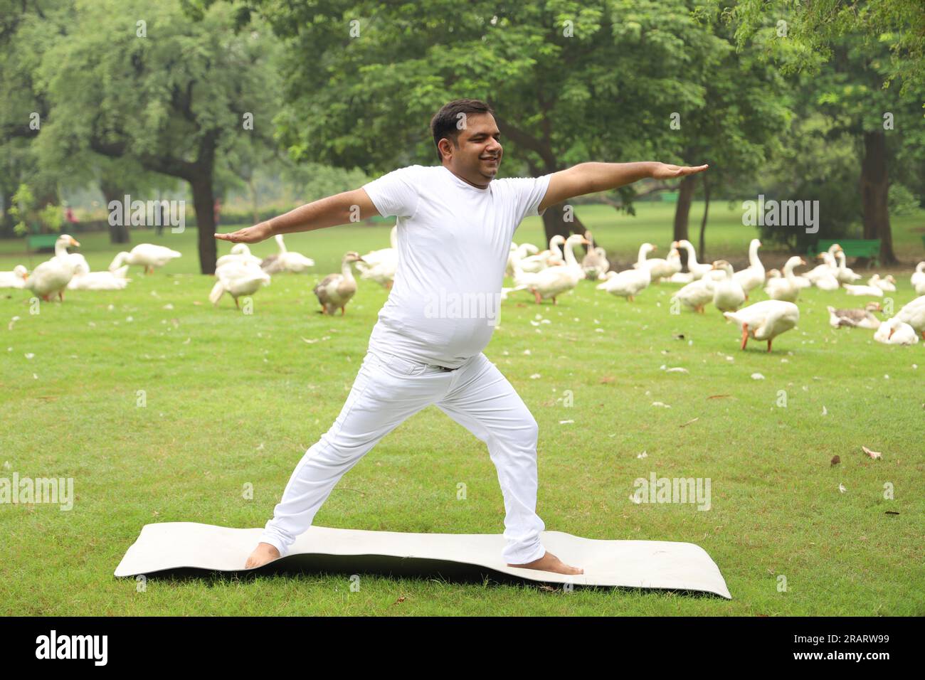 Homme obèse faisant de l'exercice et faisant du yoga poses dans un environnement vert serein tôt le matin dans le parc pour maintenir un mode de vie sain. Journée internationale du yoga. Banque D'Images