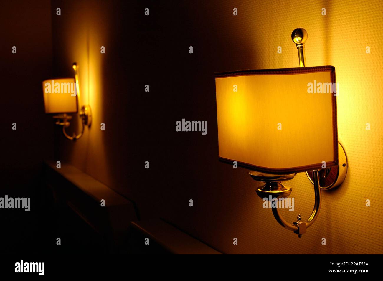 lampes allumées au-dessus du lit dans un hôtel, créant un jeu de lumière, des ombres et une atmosphère chaleureuse. Banque D'Images