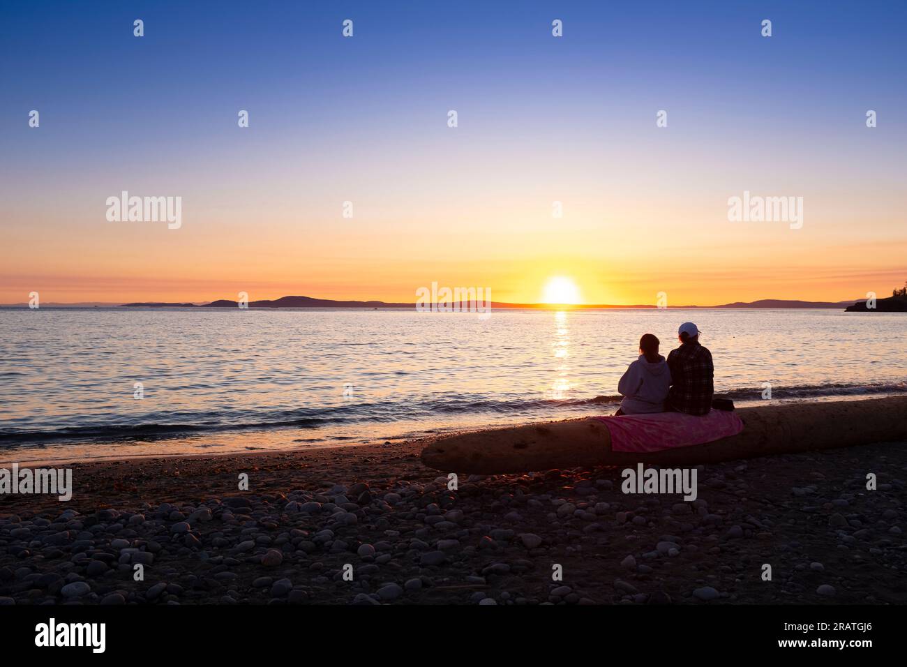 WA24514-00....WASHINGTON - deux personnes regardent le coucher du soleil à West Beach dans le parc national Deception Pass. Banque D'Images
