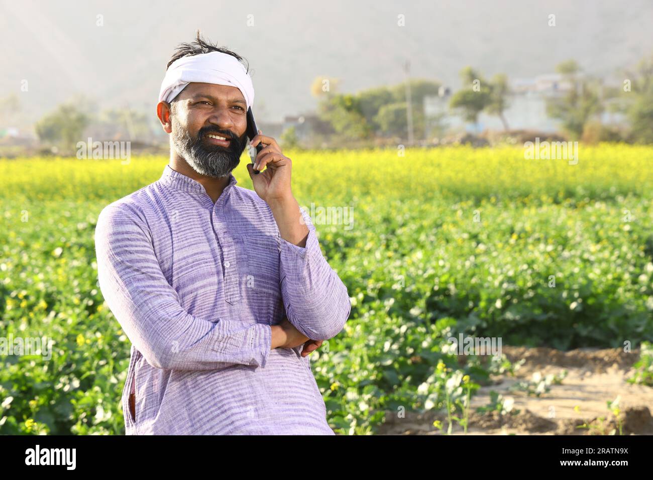 Heureux fermier indien sentant le vent tout en se tenant dans le champ en étirant ses bras. Banque D'Images