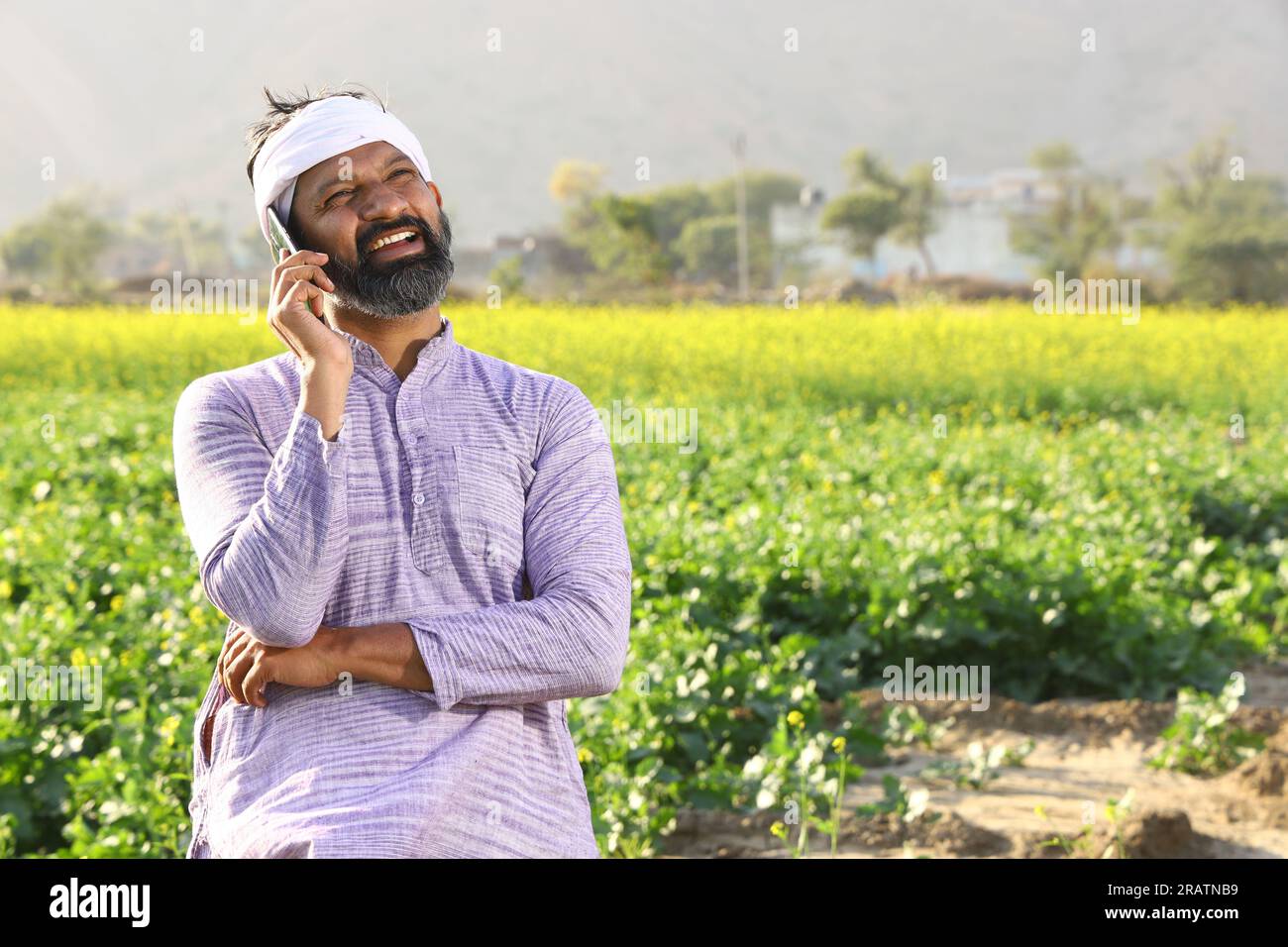 Heureux fermier indien sentant le vent tout en se tenant dans le champ en étirant ses bras. Banque D'Images