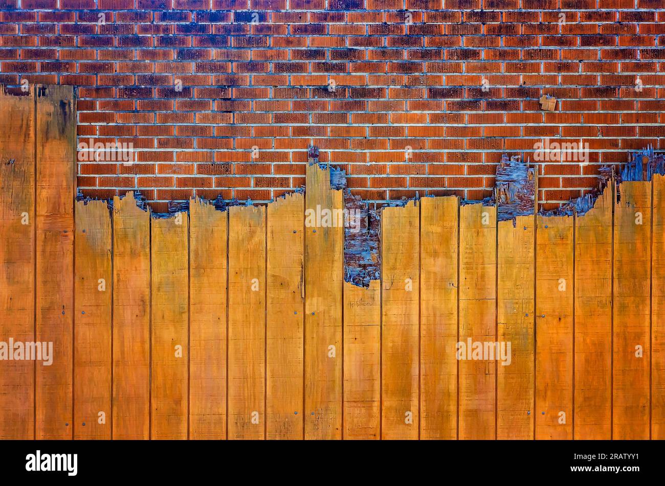 Un mur de briques est partiellement obscurci par des planches de bois cassées, le 24 juin 2023, à Moss point, Mississippi. La texture rugueuse donne un aspect rustique. Banque D'Images