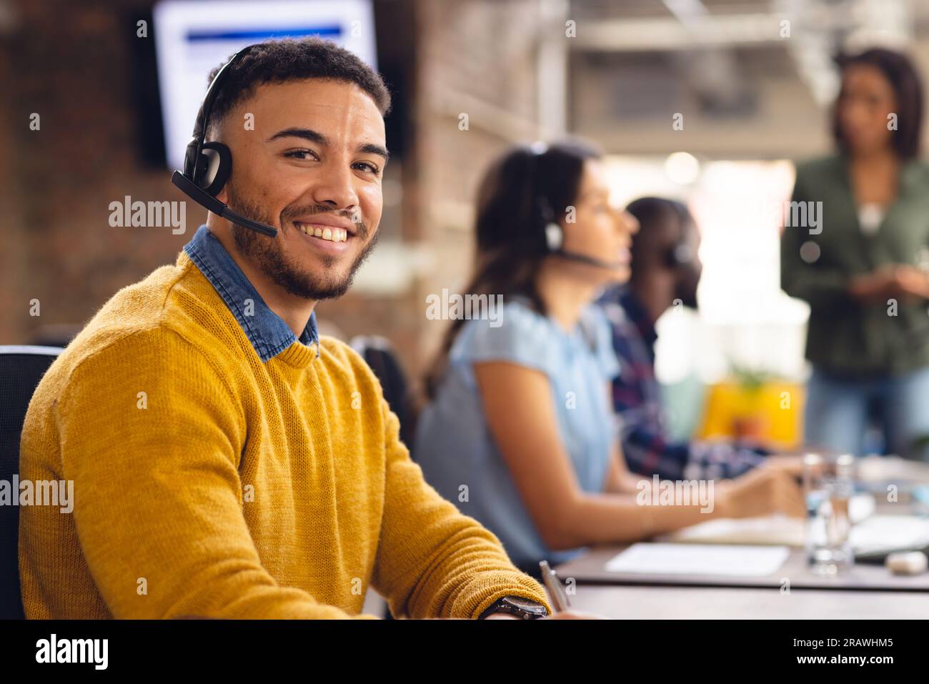 Portrait d'homme d'affaires biracial heureux utilisant le casque de téléphone et souriant au bureau. Affaires, confiance, communication et travail. Banque D'Images