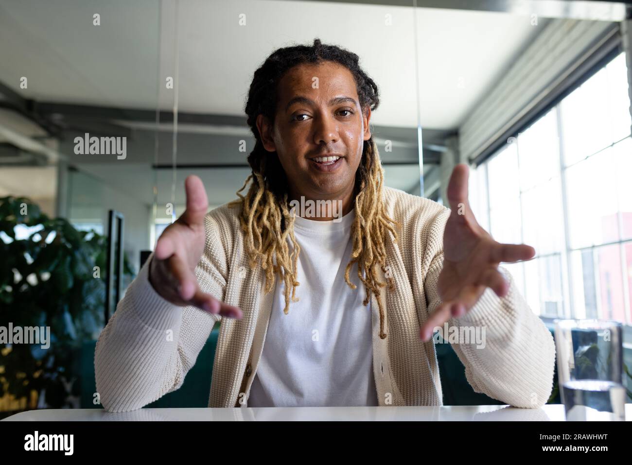 Joyeux homme d'affaires occasionnel biracial dans le bureau ayant un appel vidéo, souriant et faisant des gestes. Travail, affaires, communication et bureau occasionnel, inchangé. Banque D'Images