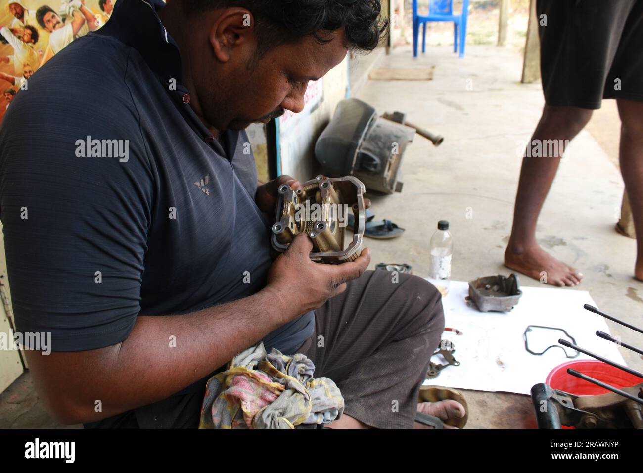 Mécanicien répare un motercycle. Un homme travaille comme mécanicien dans un atelier de réparation de motos local. Odisha, Inde. Banque D'Images Mécanicien répare un motercycle. Un homme travaille comme mécanicien dans un atelier de réparation de motos local. Odisha, Inde. Banque D'Images