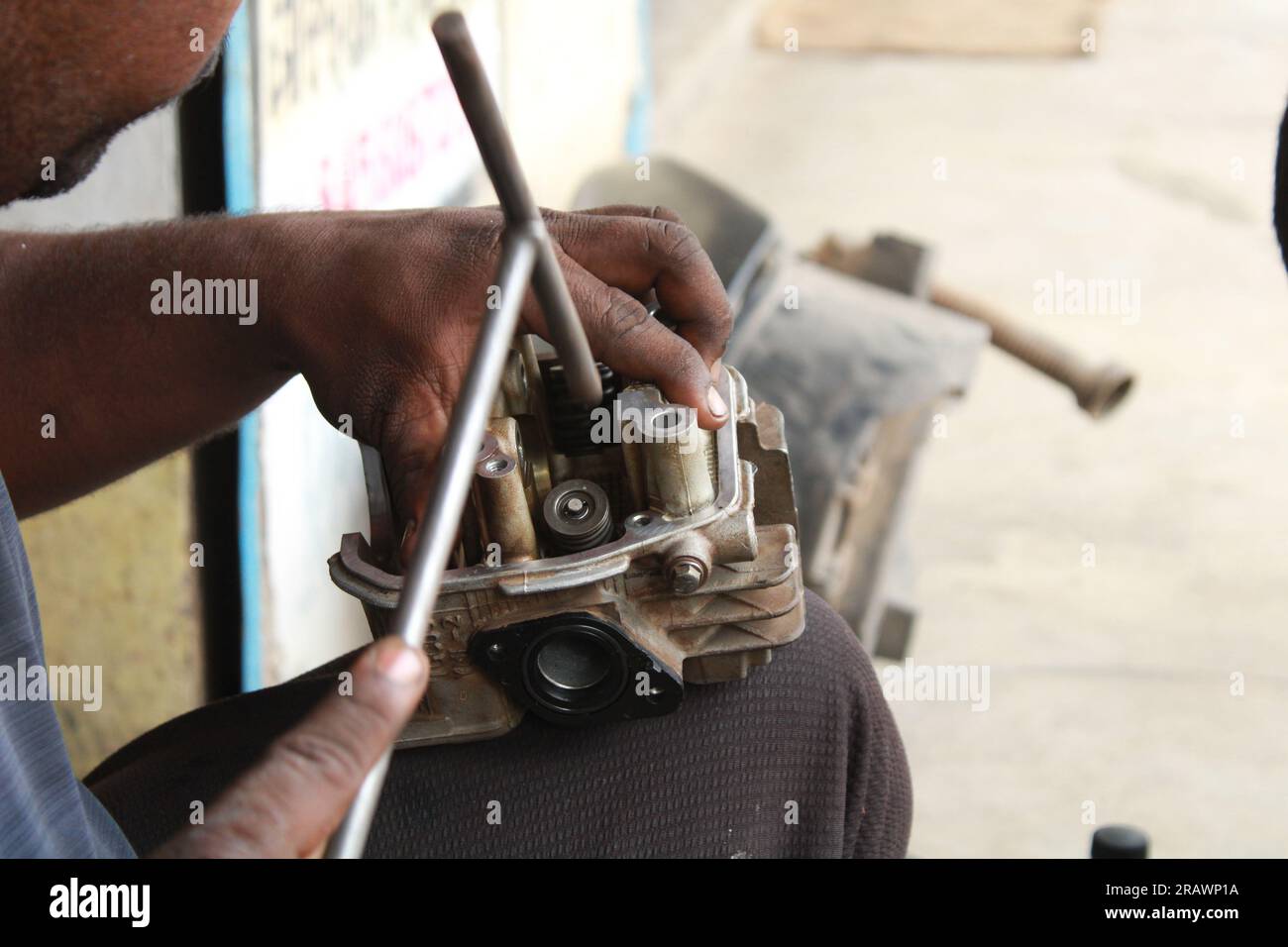 Mécanicien répare un motercycle. Un homme travaille comme mécanicien dans un atelier de réparation de motos local. Odisha, Inde. Banque D'Images Mécanicien répare un motercycle. Un homme travaille comme mécanicien dans un atelier de réparation de motos local. Odisha, Inde. Banque D'Images