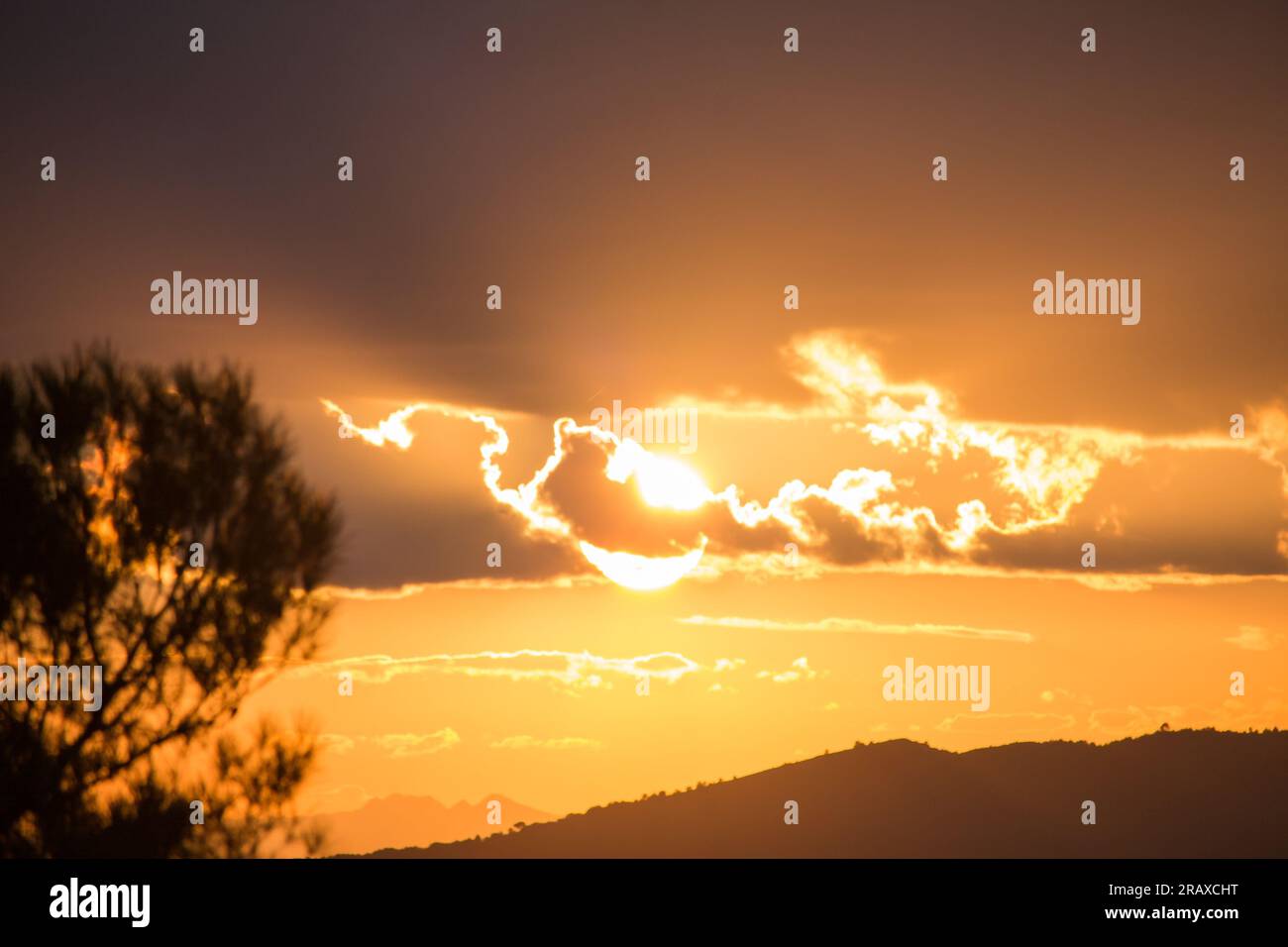 Soleil à moitié caché derrière les nuages au coucher du soleil dans la Sierra de Mariola, Communauté valencienne Banque D'Images