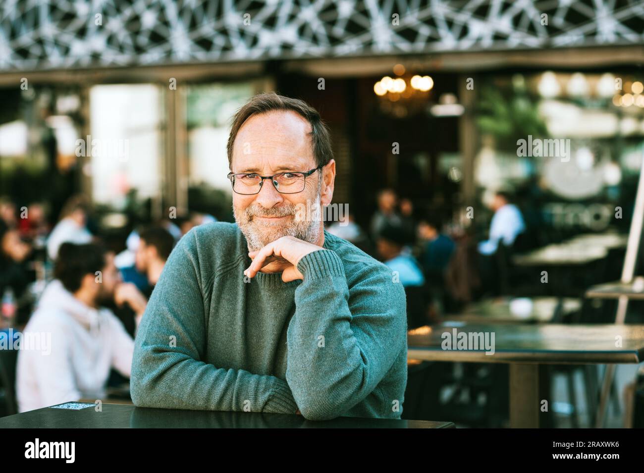 Portrait en plein air d'un homme de 50 - 55 ans portant un pull vert et des lunettes, les bras croisés Banque D'Images