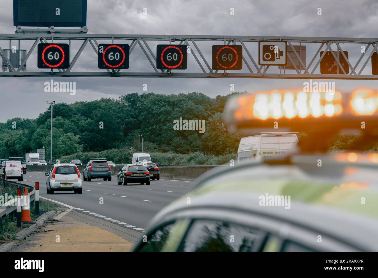 Panneaux de vitesse variable montrant une limite de vitesse de 60 mph sur un portique au-dessus d'une autoroute intelligente avec le véhicule National Highways au premier plan en Angleterre. Banque D'Images