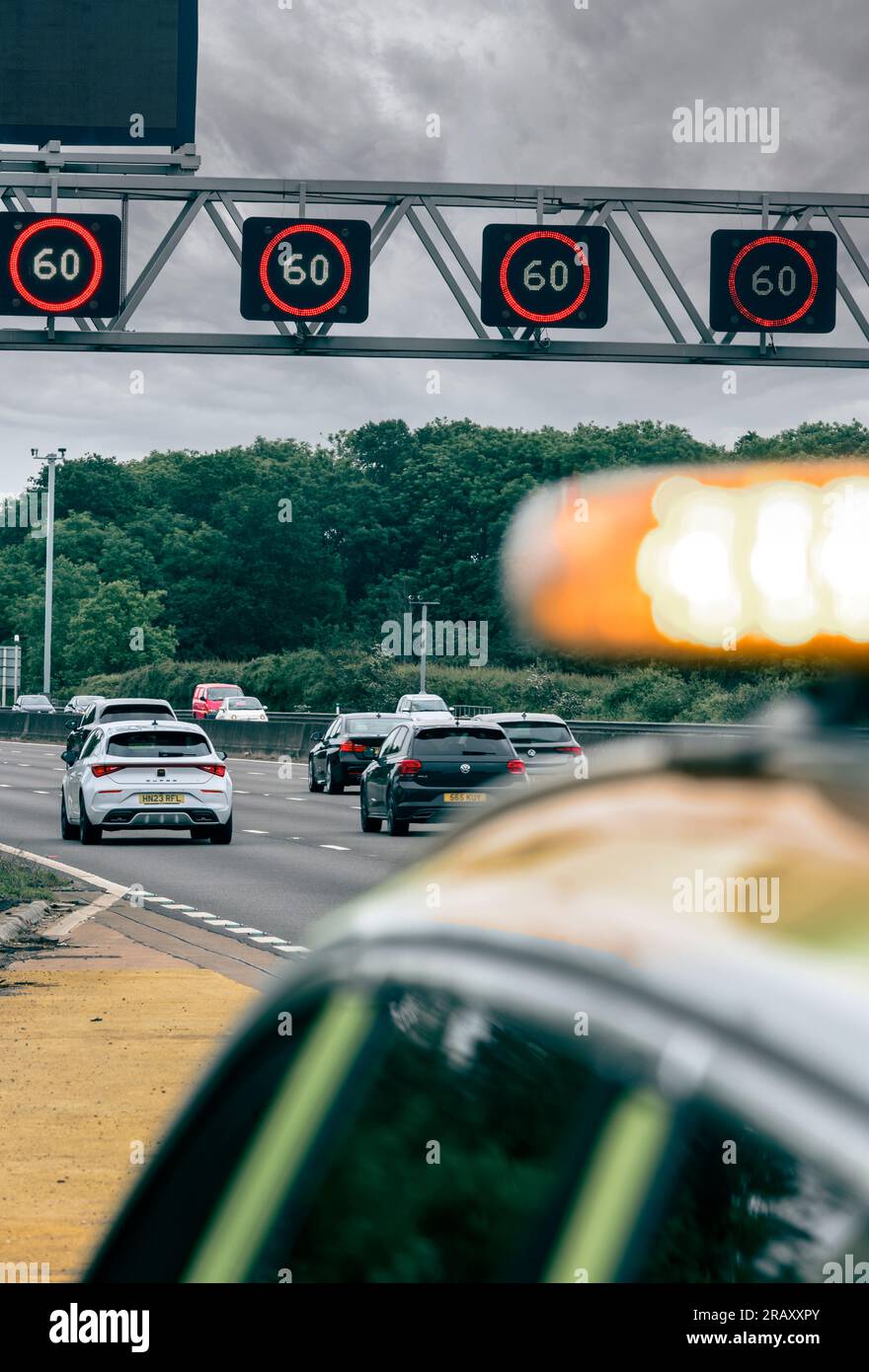 Panneaux de vitesse variable montrant une limite de vitesse de 60 mph sur un portique au-dessus d'une autoroute intelligente avec le véhicule National Highways au premier plan en Angleterre. Banque D'Images