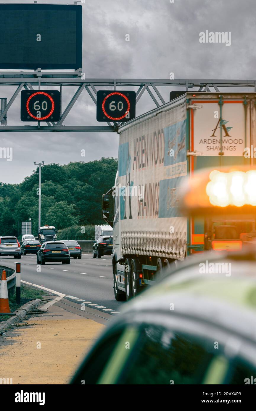 Panneaux de vitesse variable montrant une limite de vitesse de 60 mph sur un portique au-dessus d'une autoroute intelligente avec le véhicule National Highways au premier plan en Angleterre. Banque D'Images